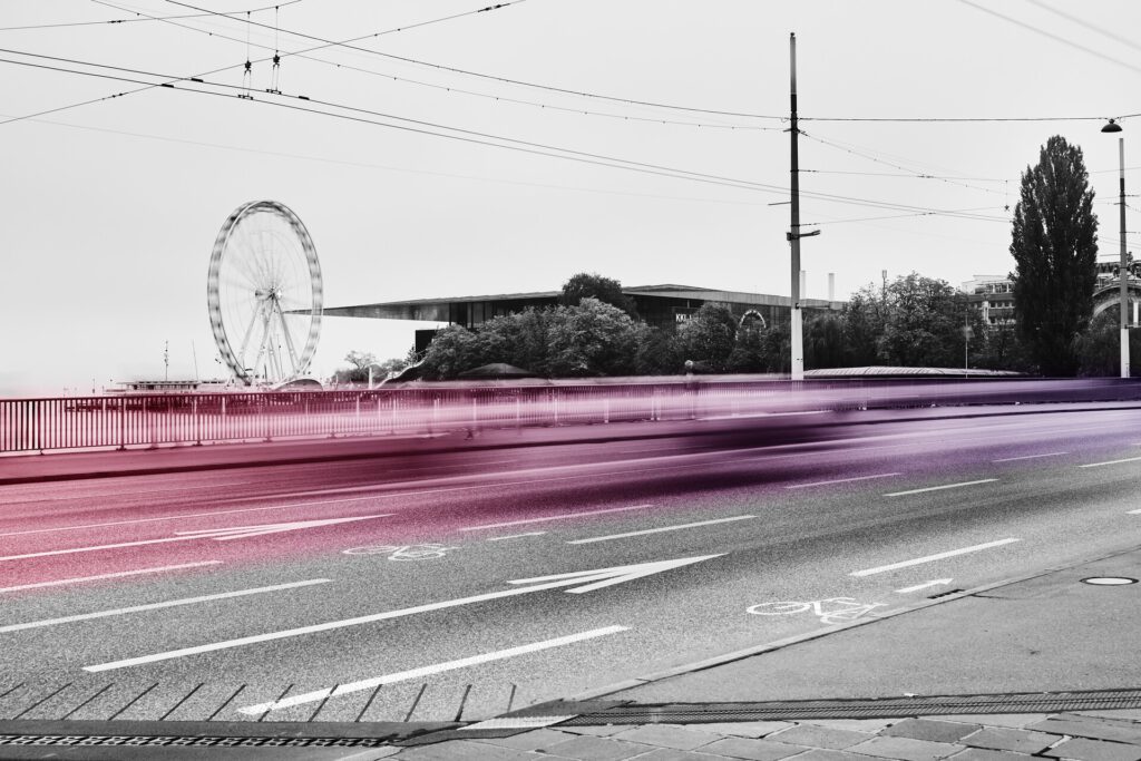 Strasse in Luzern mit Riesenrad im Hintergrund, Verkehr als Lichtspur