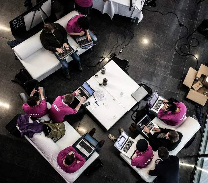 Entwicklerinnen und Entwickler arbeiten an einem Odoo-Event gemeinsam an ihren Laptops