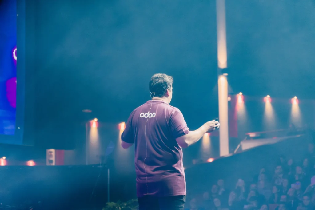 Keynote an der Odoo Experience: Referent im Odoo-Shirt auf der Bühne vor vollem Saal